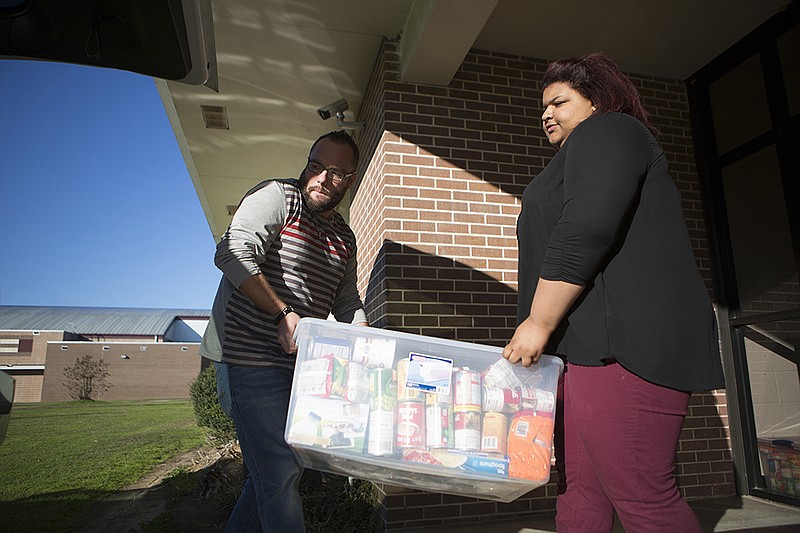 Liberty-Eylau instructor Kyle Krobot and sophomore Alyssa Burris load a bin of canned goods that will be distributed to needy families in the district. Ten families will be receiving donated food and gifts for the upcoming holiday.