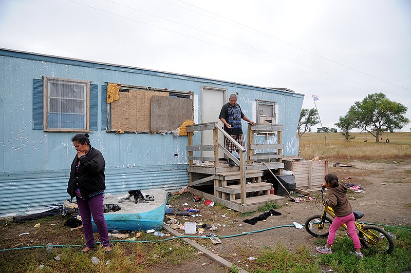 Natasha Cuny, left, her boyfriend, Raymond Eagle Hawk, center, and their daughter, Kimimila Eagle Hawk, right, stand outside Raymond Eagle Hawk's mother's trailer Sept. 30 in Wounded Knee, S.D., on the Pine Ridge Indian Reservation. Cuny, Raymond Eagle Hawk and their daughter live next door in a shed, shown below. The housing shortage on South Dakota's Pine Ridge Indian Reservation is a longstanding problem for thousands of Oglala Sioux members, but the tribe is pushing the issue into the spotlight again after severe storms and flooding in May spurred a federal disaster declaration. 
