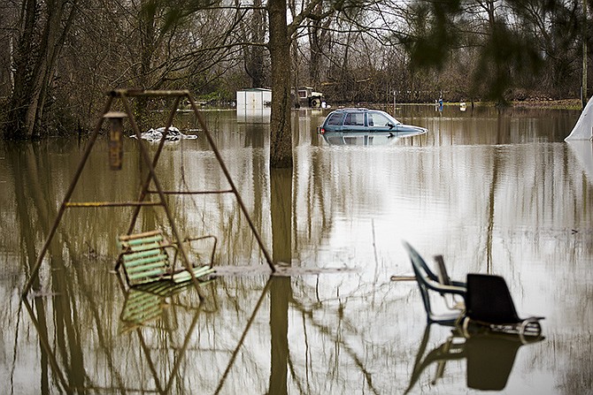 A vehicle sits underwater next to various other yard decorations outside a flooded home in Osage City Wednesday as flooding continues to be an issue for those living along the Osage River.