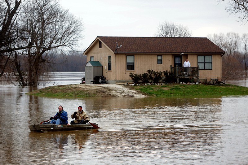 Scott Fox, front, paddles a boat with his friend, Tony Watkins, in Kimmswick Thursday. Fox decided it was time to leave his residence on Mississippi Boulevard, which was surrounded by water.