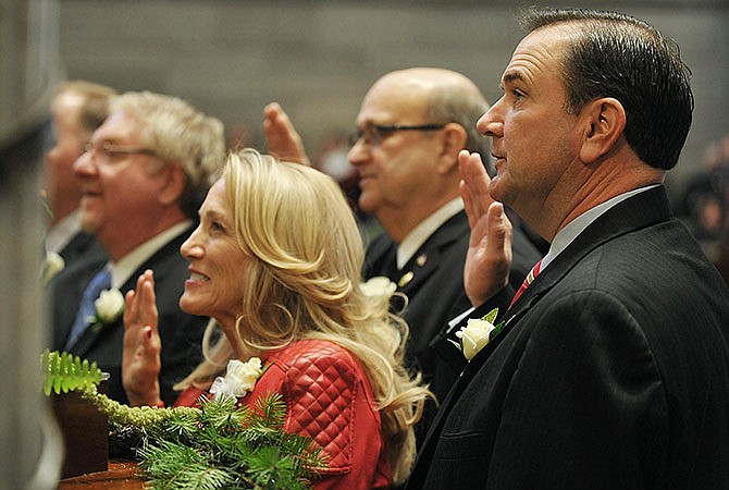 Senators Mike Kehoe, right, R-Jefferson City, and Jeanie Riddle, R-Mokane, raise their hands at the start of the 2015 Missouri legislative session as they repeat the oath of office during swearing-in ceremonies.