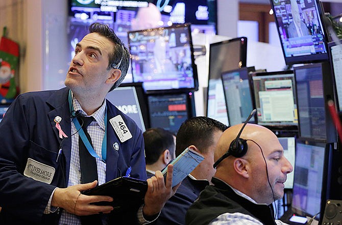 Gregory Rowe, left, with Livermore Trading Group, keeps an eye on stock prices at the New York Stock Exchange, Friday, Jan. 8, 2016.