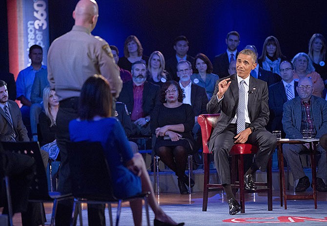President Barack Obama, right, answers questions from Arizona Sheriff Paul Babeu, left standing, during a CNN televised town hall meeting at George Mason University in Fairfax, Va., Thursday, Jan. 7, 2016. Obama's proposals to tighten gun controls rules may not accomplish his goal of keeping guns out of the hands of would-be criminals and those who aren't legally allowed to buy a weapon. In short, that's because the conditions he is changing by executive action are murkier than he made them out to be.