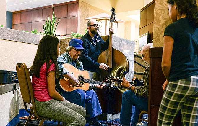 Danny Jenkins, left, of Centerville, Iowa, Jody Goodman, center, of Columbia, Mo., and Jim Goodman of Centerville play some bluegrass tunes for a curious young audience on Saturday, Jan. 9, 2016 at the Capitol Plaza Hotel in Jefferson City, Mo.