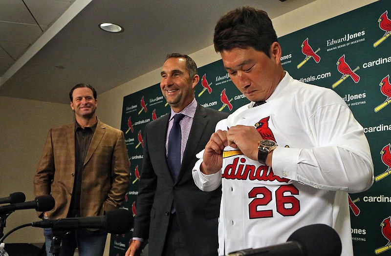 Cardinals relief pitcher Seung-Hwan Oh puts on his new jersey during a press conference Monday as manager Mike Matheny (left) and general manager John Mozeliak look on at Busch Stadium.