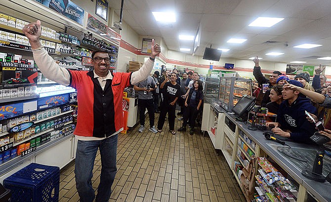 7-Eleven store clerk M. Faroqui celebrates after learning the store sold the only winning Powerball ticket on Wednesday, Jan. 13, 2016 in Chino Hills, Calif. One winning ticket was sold at the store located in suburban Los Angeles said Alex Traverso, a spokesman for California lottery. (Will Lester/The Sun via AP)