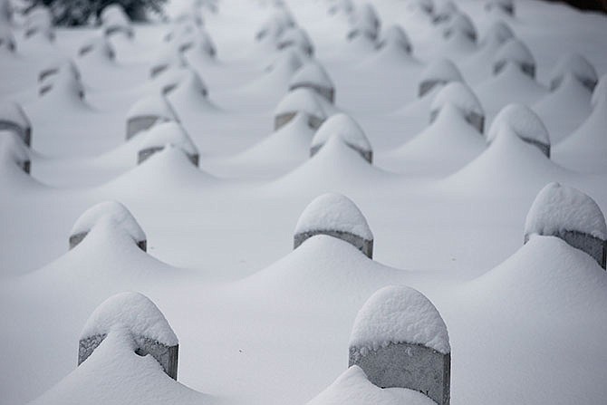 Headstones are nearly covered by snow at Arlington National Cemetery, Saturday, Jan. 23, 2016 in Arlington, Va. A blizzard with hurricane-force winds brought much of the East Coast to a standstill Saturday, dumping heavy snow, stranding tens of thousands of travelers and shutting down the nation's capital and its largest city. 