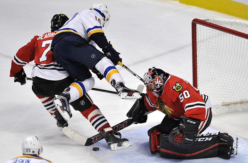 Blackhawks goalie Corey Crawford makes a save against the Blues' Scottie Upshall, who flies into the Blackhawks' Brent Seabrook during the first period of Sunday's game in Chicago.