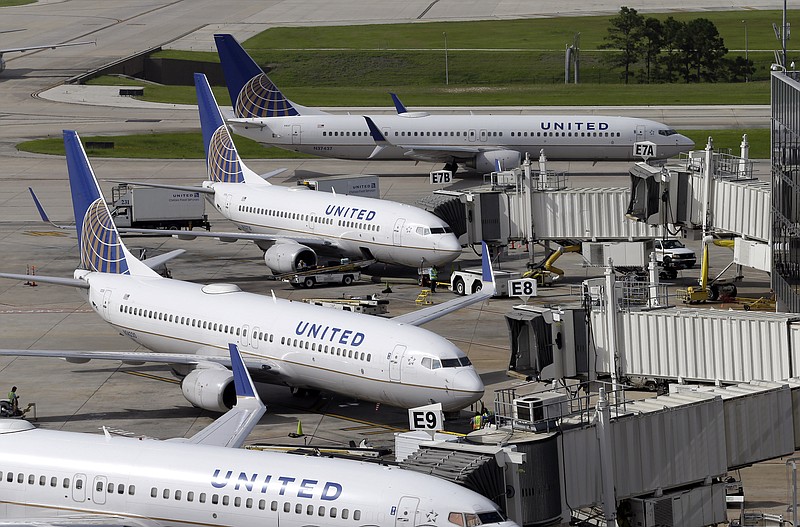 In this July 8, 2015, file photo, United Airlines planes are parked at their gates as another plane, top, taxis past them at George Bush Intercontinental Airport in Houston. 