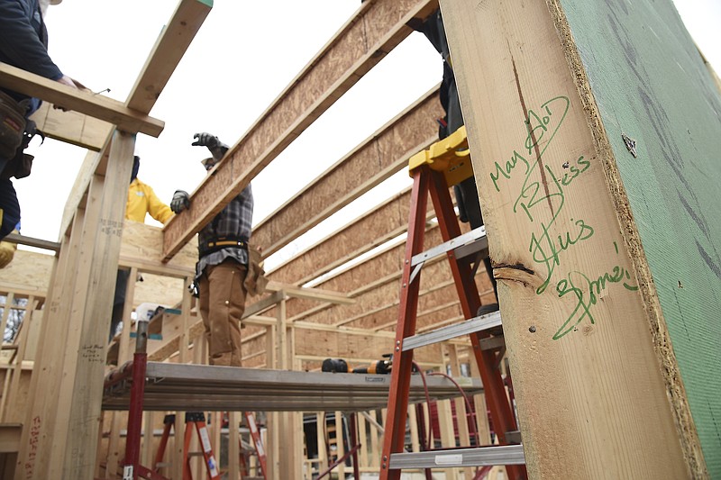 All homes constructed by River City Habitat for Humanity have handwritten messages on the framework. Volunteers work on the 94th house to be built by the local chapter.