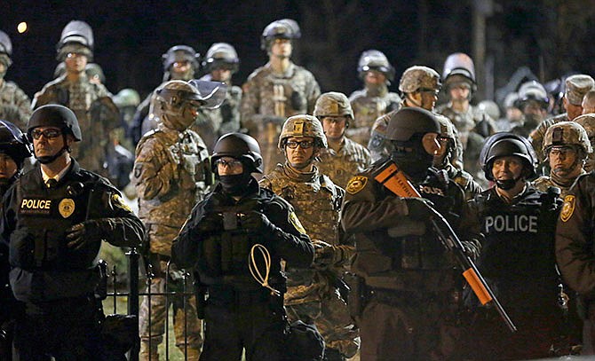 In this Friday, Nov. 28, 2014, file photo, police and Missouri National Guardsmen face protesters gathered in front of the Ferguson Police Department in Ferguson, Mo. The Justice Department has reached a tentative agreement with Ferguson on systemic changes following the fatal police shooting of 18-year-old Michael Brown in 2014, city officials announced Wednesday, Jan. 27, 2016. The recommended overhaul to the Ferguson Police Department and the city's municipal court system follows seven months of negotiations and likely averts a civil rights lawsuit that federal officials can bring against departments that resist changing their policing practices. 