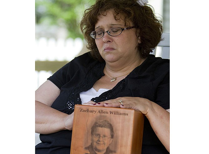 In this photo taken on May 8, 2012, Tammy Niederhelman holds an urn at her Joplin home with the remains of her son Zach Williams, who was killed in the 2011 Joplin tornado. Niederhelman said she's upset the school district won't leave an empty chair in honor of her late son during the next commencement. (Nathan Papes, The Springfield News-Leader via AP)