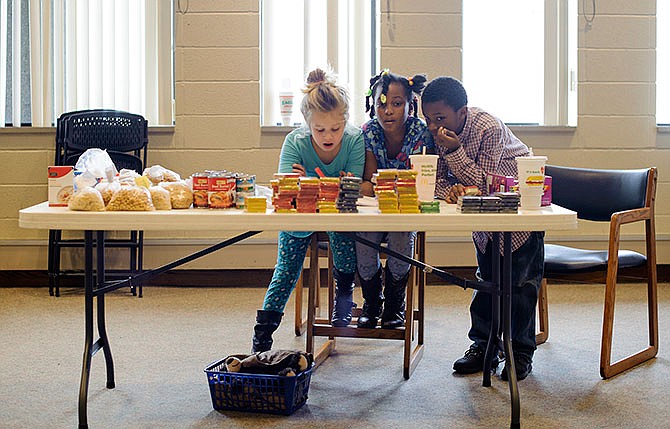 Sarah Gibbon, left, and siblings Drayton, center, and Damarion Smith staff one of several tables of provisions while volunteering to help the local homeless community during a People Helping People event Saturday afternoon at the Missouri River Regional Library in Jefferson City.