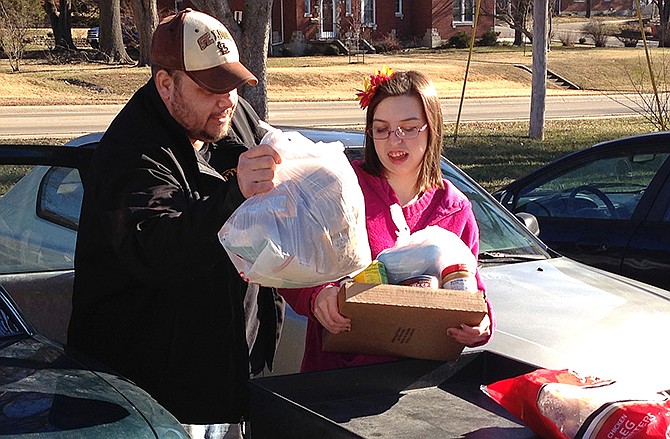 Joe Heflin, left, of Jefferson City, loads free groceries into the backseat of his car last week with the help from a volunteer at the Samaritan Center food pantry. Heflin, 33, also receives federally funded food stamp benefits. He is among the more than 1 million people nationwide whose food stamps could end in three months if he doesn't meet work requirements or receive a disability exemption. 