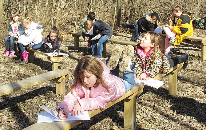 Students of Jessica Huyser's fourth-grade class at Hatton-McCredie sit and draw pictures or write about their
time in the outdoor classroom Tuesday. The Fulton school received a $2,500 Monsanto grant to make improvements to the classroom, including building two bridges for a safer passage to the area.