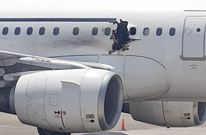 A hole is shown in a plane operated by Daallo Airlines as it sits on the runway of the airport in Mogadishu, Somalia. The gaping hole in the commercial airliner forced it to make an emergency landing at Mogadishu's international airport late Tuesday.