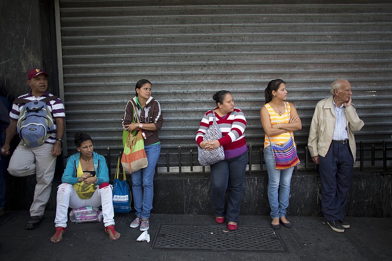 In this Wednesday, Jan. 27, 2016, file photo, people wait in line to buy groceries at government regulated prices in Caracas, Venezuela. Cheap oil prices are wreaking havoc and causing uncertainty for some governments and businesses, while creating financial windfalls for others. Venezuela's government earns 95 percent of its export income from oil, and its economy was already unraveling before the plunge in oil prices. Long lines for food and other scarce goods are commonplace.