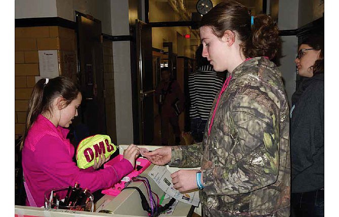 Karmon Mobley-Doan uses her Hornet Bucks to pay Summer Hood for a purchase at the Positive Behavior Intervention Support store at Fulton Middle School. The program rewards students' positive behavior by giving them Hornet Bucks, which can be used to purchase rewards as varied as allotted time to play a computer game at school or getting a treat at a local business. Josie Brennan stands in the background.