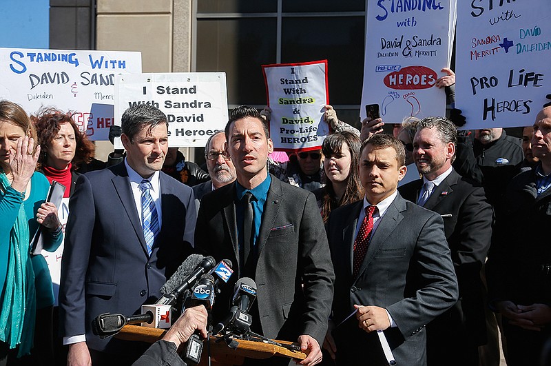 Davids Daleiden, center, one of the two anti-abortion activists indicted last week speaks to media and supporters after turning himself in to authorities Thursday, Feb. 4, 2016, in Houston. Daleiden and Sandra Merritt are charged with tampering with a governmental record, a felony punishable by up to 20 years in prison. 