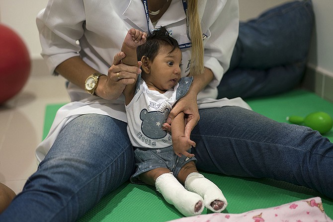 A therapist works with microcephaly patient Luana Vitoria, who is wearing corrective leg casts, during a physical stimulation session Thursday at the Altino Ventura Foundation, a treatment center that provides free health care, in Recife, Pernambuco state, Brazil. 