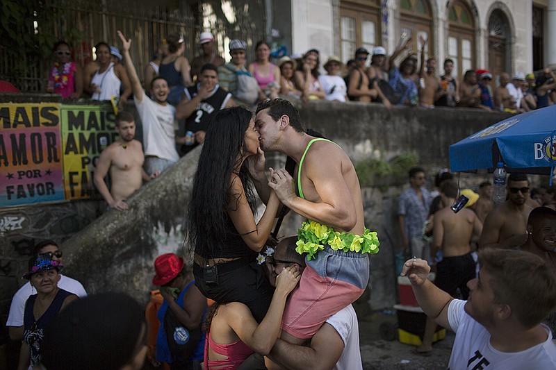 A couple kisses during the "Carmelitas" block party, during Carnival celebrations in Rio de Janeiro, Brazil, Friday, Feb. 5, 2016. Top Brazilian Health officials said this Friday that the active Zika virus has been found in urine and saliva samples, cautioning that further study is needed to determine whether the mosquito-borne virus in those body fluids is capable of infecting people.