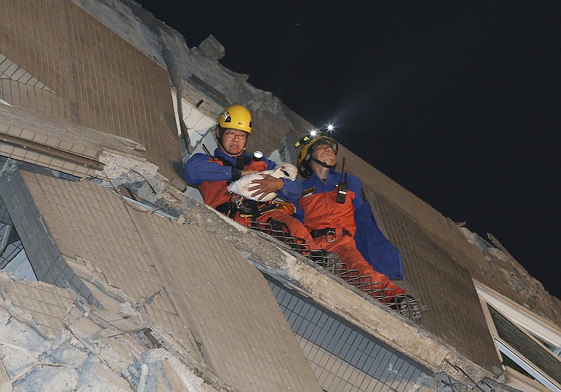 Rescue workers carry a baby swaddled in a cloth from the rubble of a toppled building after an earthquake Saturday, Feb. 6, 2016, in Tainan, Taiwan. The 6.4-magnitude earthquake struck southern Taiwan early Saturday, toppling at least one high-rise residential building and trapping people inside. Firefighters rushed to pull out survivors.