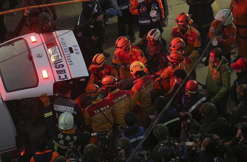 Rescue workers carry 28-year-old Vietnamese woman identified as Chen Mei-jih, rescued from the rubble of a collapsed building complex to a waiting ambulance Monday.