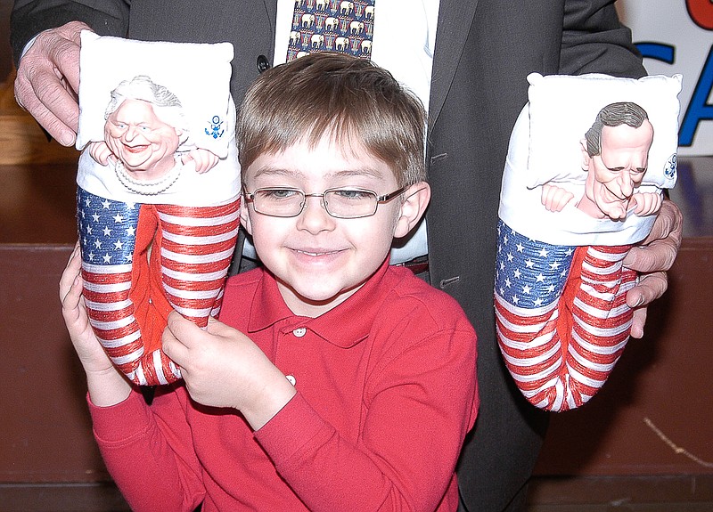 Landon Leonard, St. Louis, accepts the traveling door prize, the George and Barbara Bush house slippers. The young man is grandson of Abe Rohrbach.