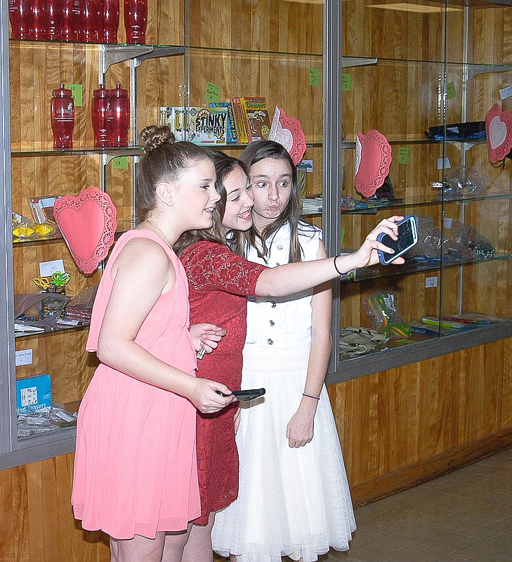 It's hard for the girls at the Middle School Valentine's Dance to resist taking a selfie with friends.