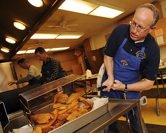 David Gramlich dumps out a freshly fried batch of swai filets as he and several other Knights hustle to keep pace with demand during a previous Knights of Columbus's Lenten Fish Fry at the Cathedral of St. Joseph.