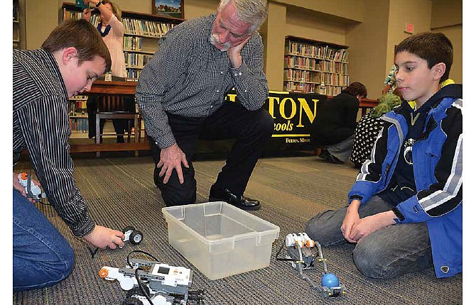 Fulton Middle School students Connor Duncan (left) and Jacob Moak explain their robotics project to school board member Rodney Lattey.