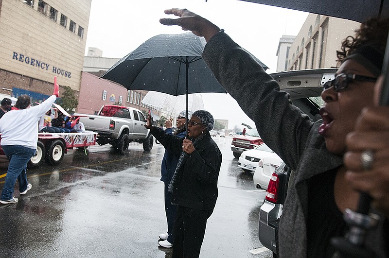 Ella Reece, right, Ruby Hanson, center, and Niki Reece, didn't let the rain stop them from cheering on the participants in the 24th annual Twin City Black History Association Parade Feb. 21, 2015, on Broad Street in downtown Texarkana. 