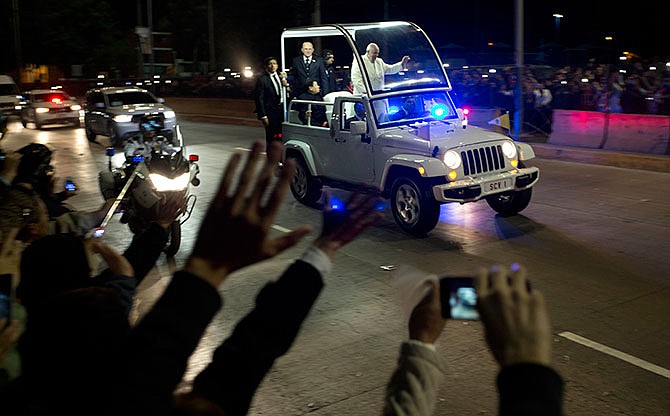 Pope Francis waves to people from the popemobile along his route to the Apostolic Nunciature, the Vatican's diplomatic mission, in Mexico City, Friday, Feb. 12, 2016. The pontiff is in Mexico for a week-long visit.
