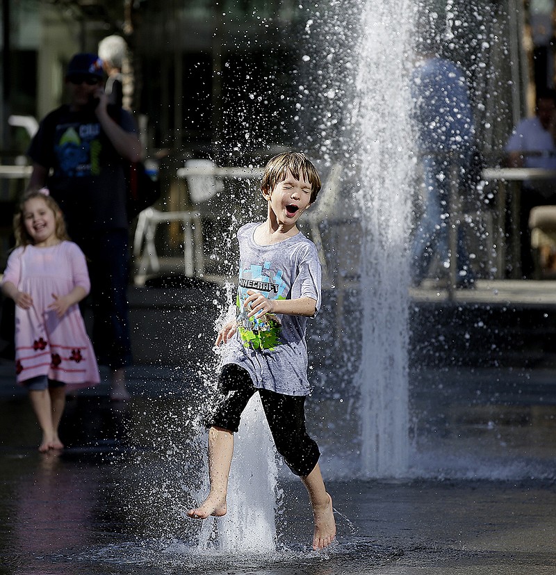 Brock Harold runs through water Thursday, Feb. 11, 2016 in downtown Dallas. Springlike weather has moved into Texas, making being outdoors during winter enjoyable. 