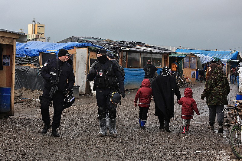 In this Feb. 5, 2016 photo, French riot police officers patrol in the migrant camp in Calais, north of France. Mysterious armed groups are on the prowl, targeting migrants in night attacks in Calais and other migrant haunts in northern France, sowing fear among the displaced travelers living in squalid slums in hopes of sneaking into Britain but also deepening concerns Calais is becoming a tinderbox fueled with anti-migrant rage and a breeding ground for nationalists.