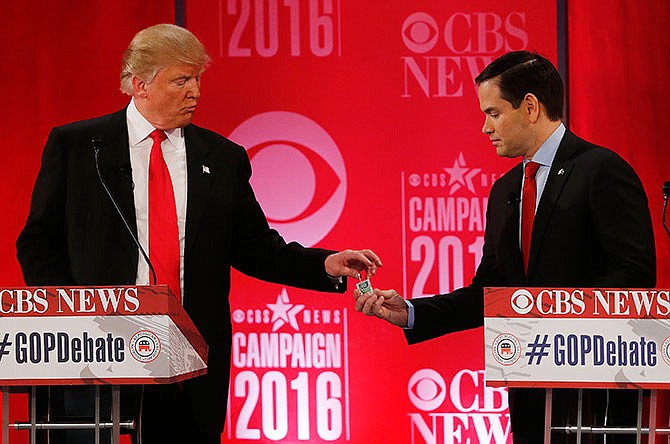 Republican presidential candidate, Sen. Marco Rubio, R-Fla., right, hands Republican presidential candidate, businessman Donald Trump a tic tac container at a break during the CBS News Republican presidential debate at the Peace Center, Saturday, Feb. 13, 2016, in Greenville, S.C.
