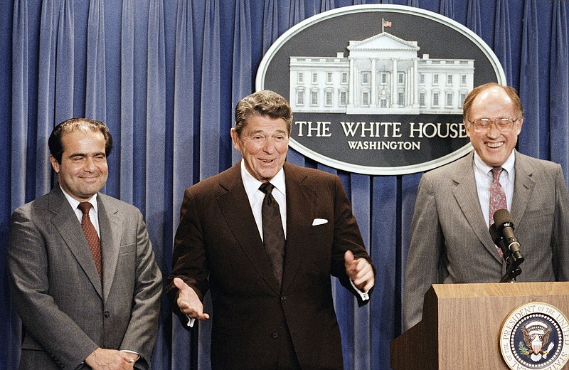In this June 17, 1986, file photo, President Ronald Reagan speaks at a news briefing at the White House in Washington, where he announced the nomination of Antonin Scalia, left, to the Supreme Court as a result of Chief Justice Warren E. Burger's resignation. William Rehnquist is at right. The U.S. Marshals Service confirmed Saturday, Feb. 13, 2016, that Justice Scalia has died at the age of 79.