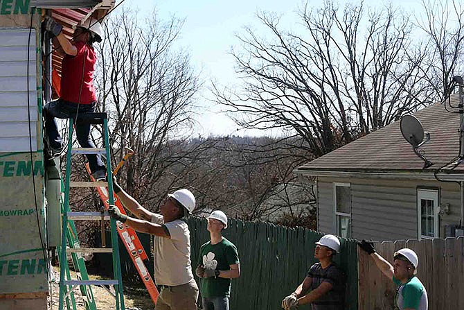 From left, Rebekah Espinoza works on house siding while Roman Mireles holds the ladder, and William Ward, Miguel Tafolla and Octavio Zaragoza watch Saturday during rehab work of a Habitat for Humanity house on Harding Street. Marines from Ft. Leonard Wood volunteered to help work on the house.