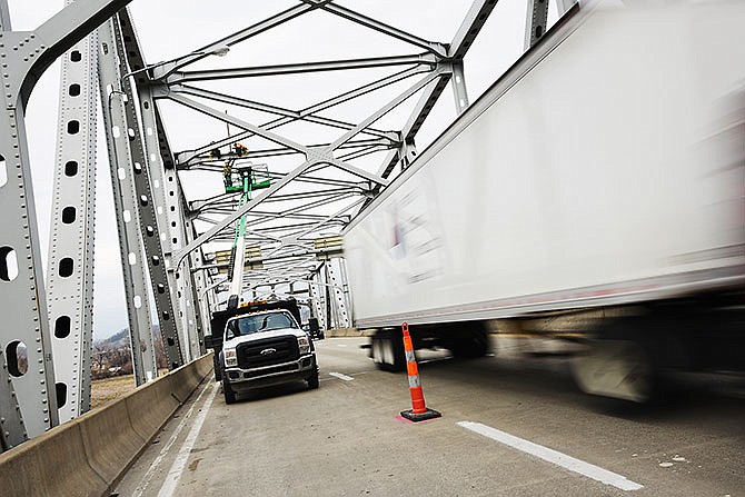 As a truck passes by, workers from Saffo Contractors prepare Thursday to enclose the westbound Missouri River bridge in Jefferson City for sandblasting and painting, which is expected to begin in April.