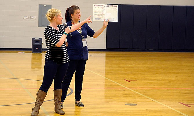 Courtney Soltvedt, a program representative for Usborne Books & More Reach for the Stars, and reading teacher Dani Schaeffer explain how to log reading minutes. The program challenges Eugene Elementary students to read 30 minutes each day for 14 days.