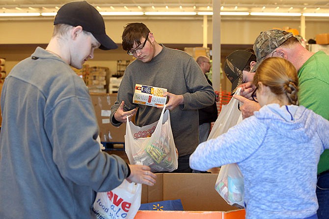 Patrick Rogers, 16, center, inspects donated food supplies Saturday at Save-A-Lot. Volunteers were collecting Scouting for Food donations, which go to the Samaritan Center.