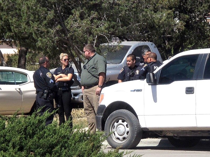 Artesia Police Department officers join New Mexico State Police, SWAT, and other agencies gather while investigating a lead in the morning at a home in Artesia, N.M., Thursday, March 10, 2016. Authorities were searching Thursday for two violent convicts who escaped from a prisoner transport van and likely got a head start of several hours in a remote area of New Mexico before guards realized they were gone. 