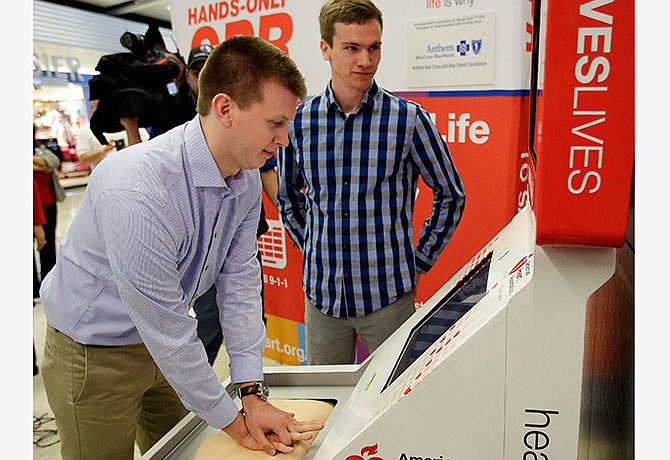 In this Thursday, March 10, 2016 file photo, Sean Ferguson, left, practices CPR on a kiosk like the one Matt Lickenbrock, right, learned on two days before saving Ferguson's life, during a news conference at the Indianapolis International Airport in Indianapolis. Lickebrock learned CPR from a kiosk at the Dallas Fort Worth airport only two days before administering it to Ferguson following a lighting strike.