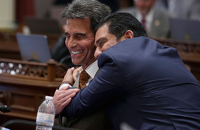 State Sen. Mark Leno, D-San Francisco, left, one of the authors of a bill to raise California's minimum wage, is hugged by Sen. Ben Hueso, D-San Diego, as the Senate voted on the bill, Thursday, March 31, 2016, in Sacramento, Calif. The bill, SB3, to gradually raise the state's minimum wage to a nation-leading $15 an hour by 2022, was approved by both houses of the Legislature and sent to Gov. Jerry Brown.