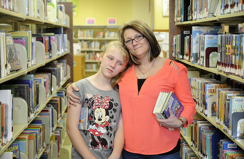 Tiara Maasen, 11, of Rich Fountain, poses for a photo with her mother, Tammy Maasen, at the Missouri River Regional Library - one of Tiara's favorite spots. In 2007, Tiara was diagnosed with autism. 
