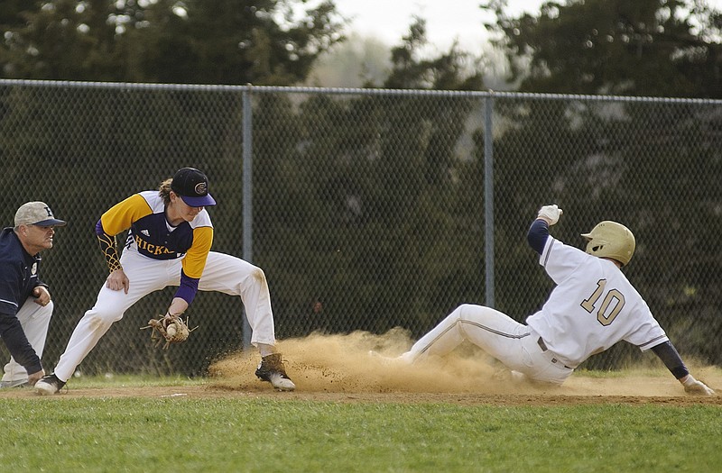 Helias' Dylan Gaines slides safely into third base after advancing on an errant relay throw to the plate as head coach Chris Wyrick orders him to get down during Wednesday afternoon's game against Hickman at American Legion Sports Complex.