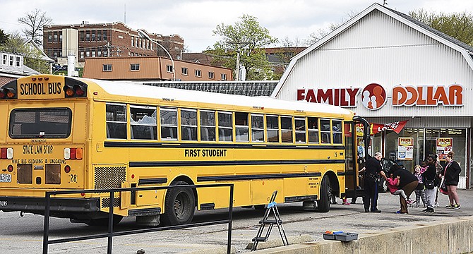 Students are removed from the school bus Wednesday in the parking lot of Family Dollar on Madison Street after an afternoon shooting. The bus, containing 21 East Elementary School students, was struck by four bullets, shattering the window at rear. None of the students or the driver was injured, and another bus was brought to the scene to take the students home.