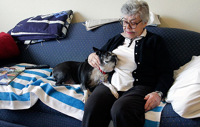 In this March 9, 2016, photo, Elizabeth Kennedy, pets her dog, Dolly, in her living room at TigerPlace, a retirement community in Columbia, Mo. Kennedy is going to be 90 years old in May, and she believes that Dolly, a 12-year-old Boston terrier, is the last dog she'll ever have. For the last six years, Dolly has been one of her best friends. (Kelsey Walling/Missourian via AP)