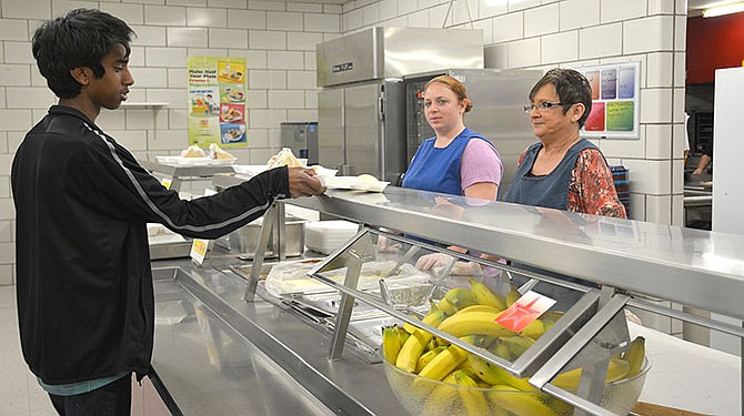 Leslie Bruce (center) and Jessie Pendegraft assist student Naman Dreyer with his lunch-time options.
