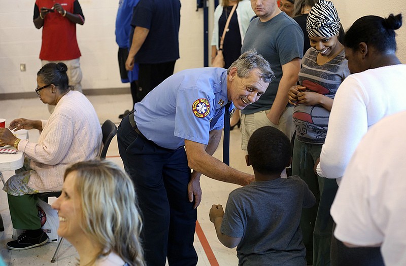 Capt. Charles Skornia, center, interacts with Joshua McPherson, 5, at bottom, while McPhersonâ€™s motherâ€™s friend Lovee Garrard, upper right corner, smiles during Skorniaâ€™s retirement party at the Salvation Army on Thursday. Skornia chose to hold a walk-in BBQ dinner for family, friends and those in need for his celebration. 